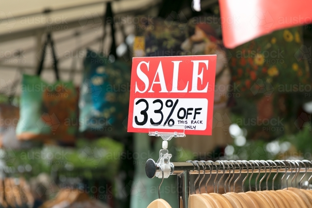 Image of Outdoor sale sign on clothing rack at retail store - Austockphoto