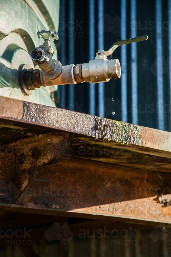 Outside rain water tap on rusty, moss covered tank stand - Australian Stock Image