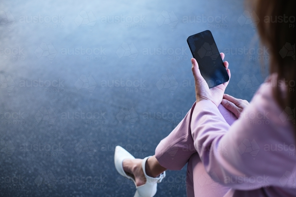 Over the shoulder shot of woman typing on mobile phone - Australian Stock Image