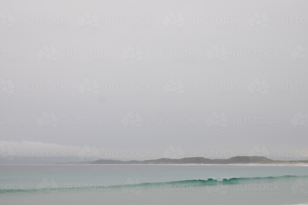 Overcast seascape with single wave crashing along remote deserted coastline - Australian Stock Image