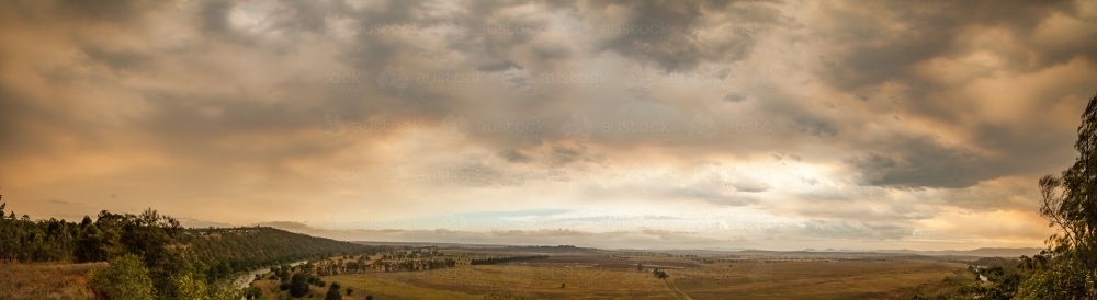 Overcast sky filled with orange smoke from distant bushfires above dry paddocks - Australian Stock Image
