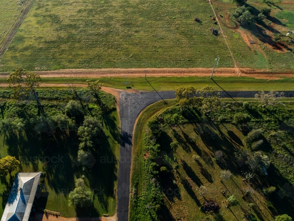 Overhead aerial view of right angled bend in country road beside farmland - Australian Stock Image