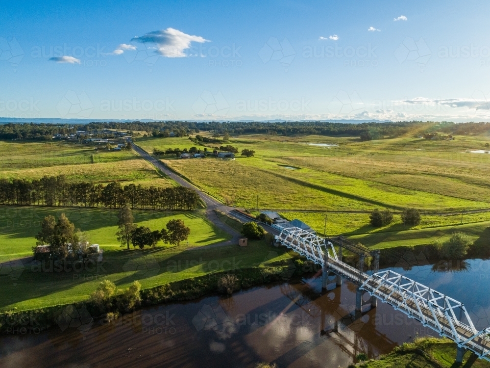 overhead-braced timber truss road bridge across river in green farmland - Australian Stock Image