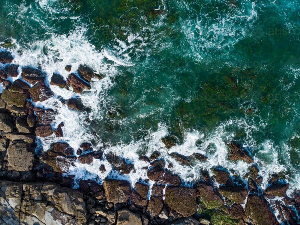 Overhead close up coastal view of ocean waves crashing onto rocky coast on the Australian shore - Australian Stock Image