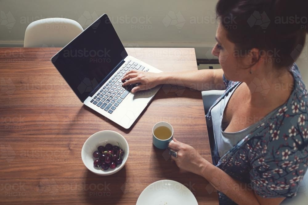 Overhead of a woman working on her laptop at home - Australian Stock Image