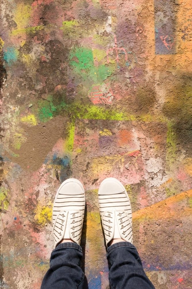 overhead of feet on a spray painted laneway - Australian Stock Image