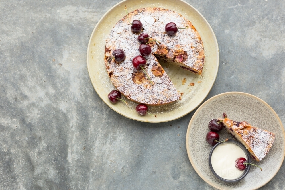 Overhead shot of almond and cherry cake with one slice removed on a separate plate - Australian Stock Image