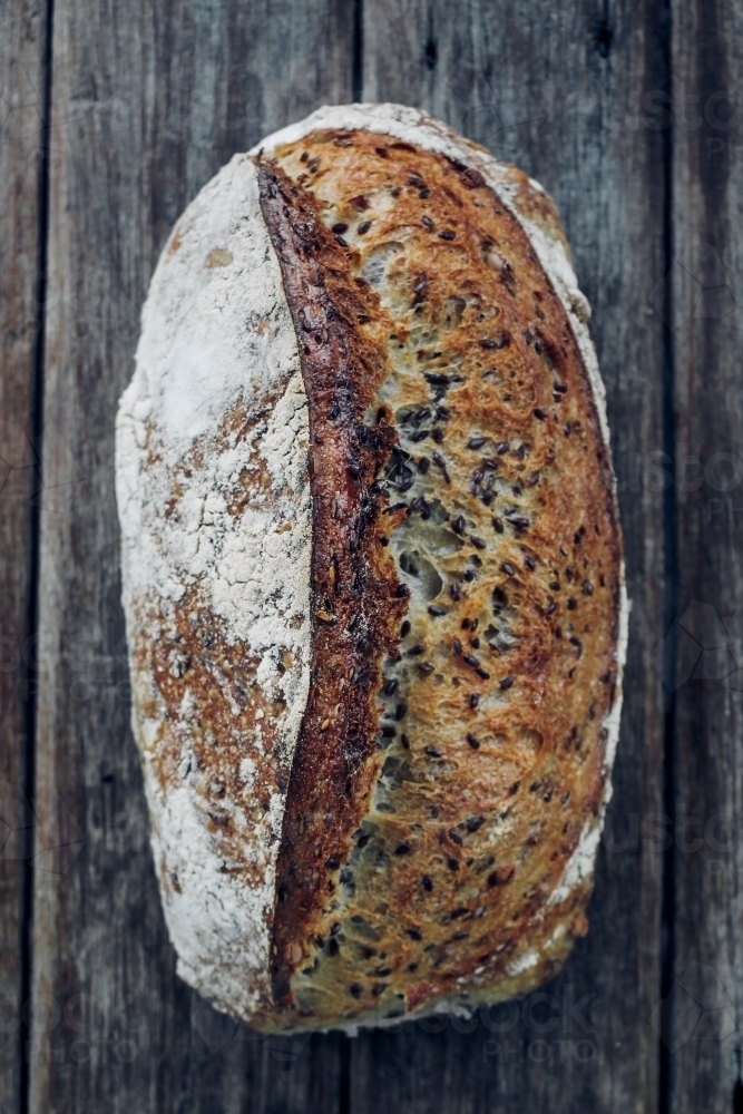Overhead shot of organic soybean and linseed sourdough on wooden bench - Australian Stock Image