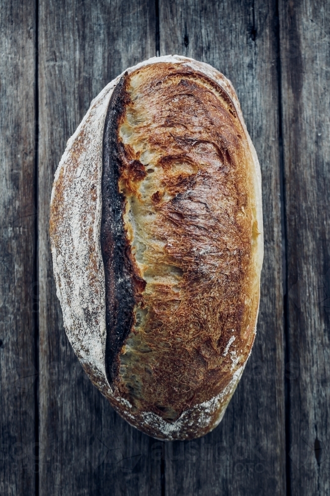 Overhead shot of organic white sourdough on wooden bench - Australian Stock Image