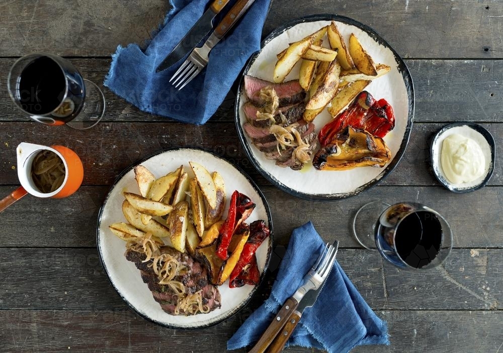 Overhead shot of steak and roasted vegetable dish on rustic table - Australian Stock Image
