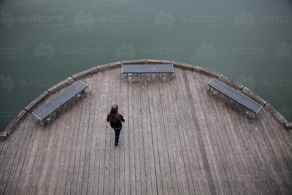 Overhead shot of teen girl walking over wooden Newcastle ferry wharf - Australian Stock Image