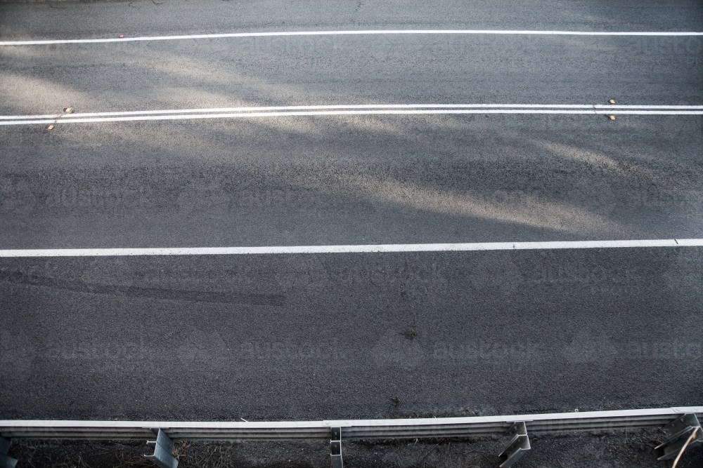 Overhead shot of unbroken white lines on a sealed road - Australian Stock Image
