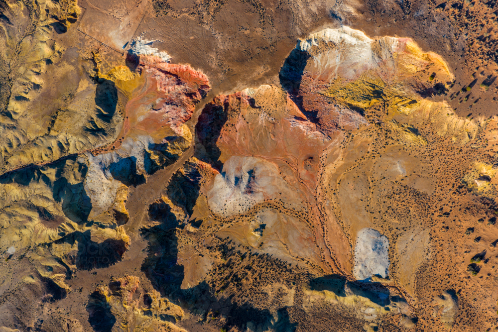 Overhead shot of white erosion patterns and green shrubs on orange desert soil - Australian Stock Image