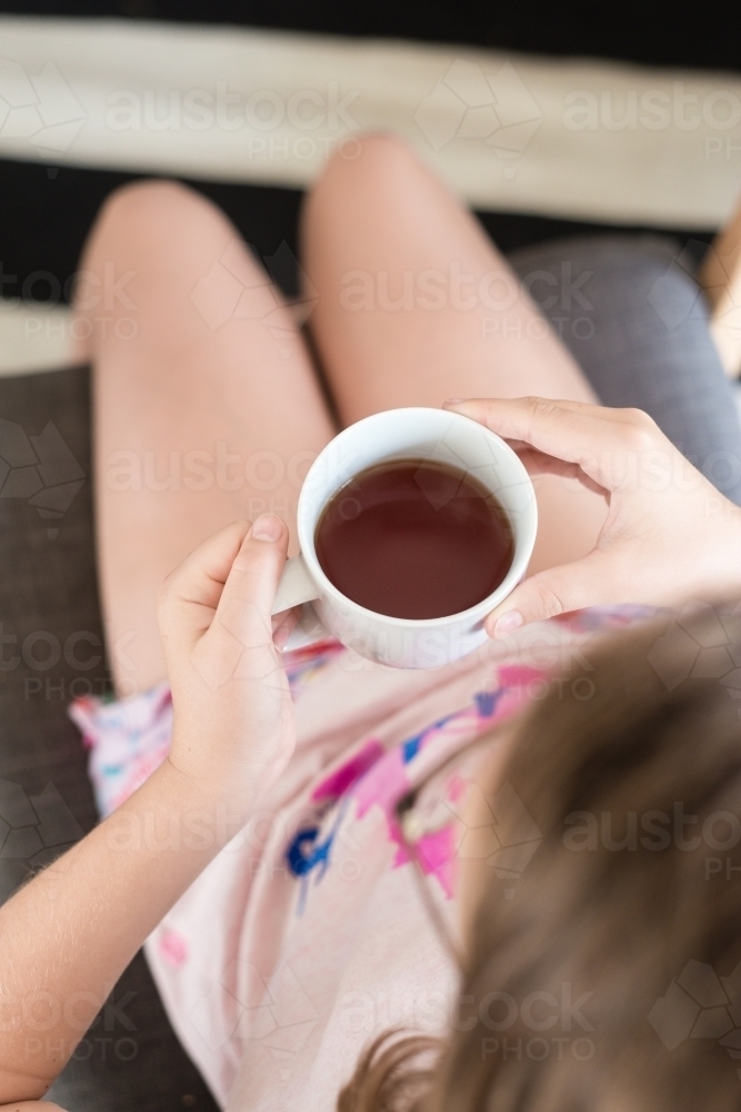 Overhead view of a teen girl drinking black tea - Australian Stock Image
