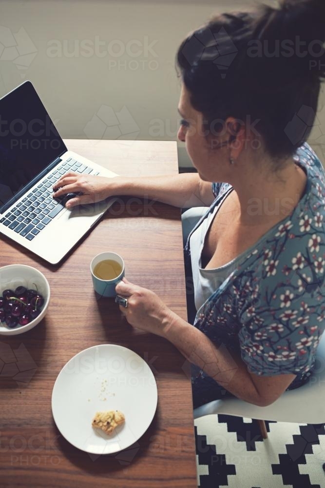 Overhead view of a woman working on laptop at home - Australian Stock Image