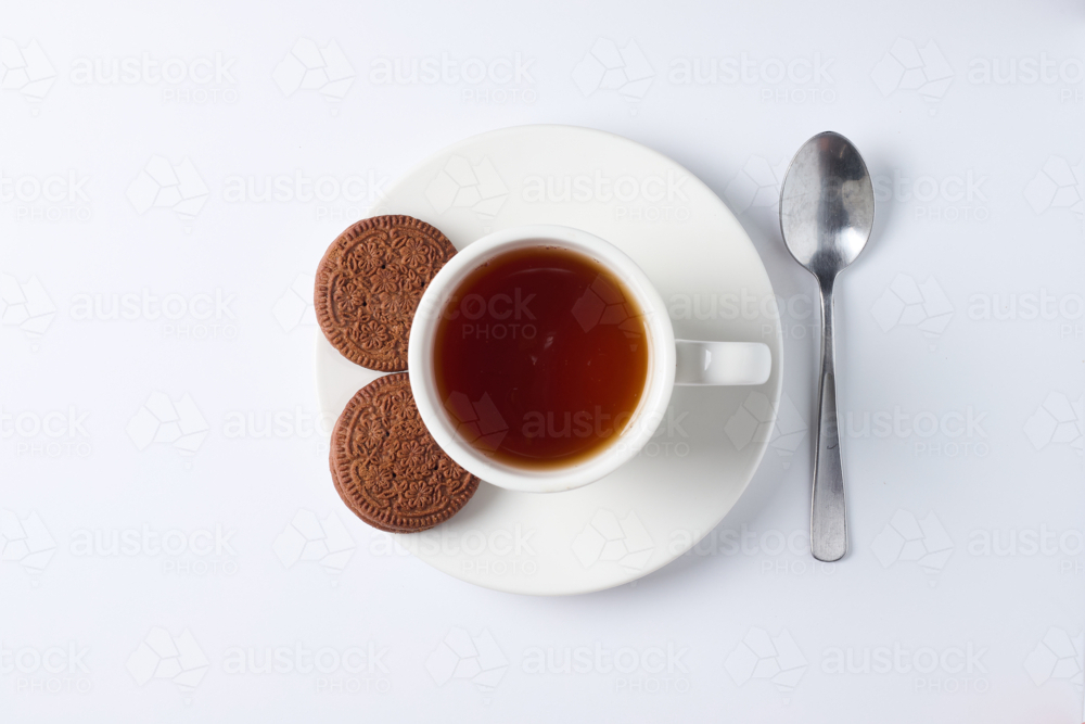overhead view of cup of tea with chocolate cream biscuits - Australian Stock Image