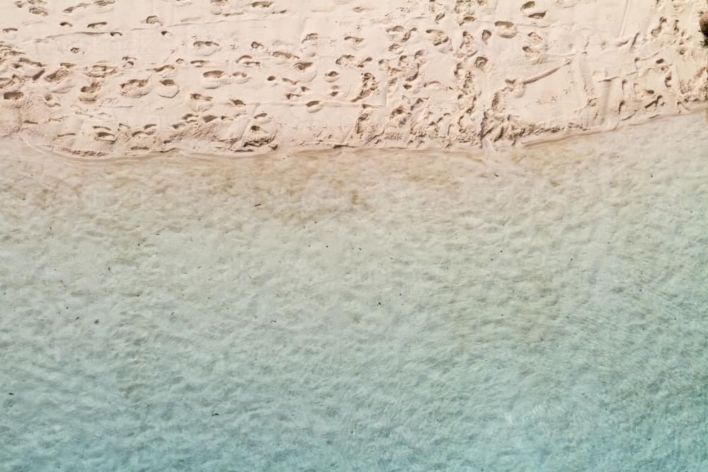 Overhead view of sandy beach waters edge with aqua blue water - Australian Stock Image