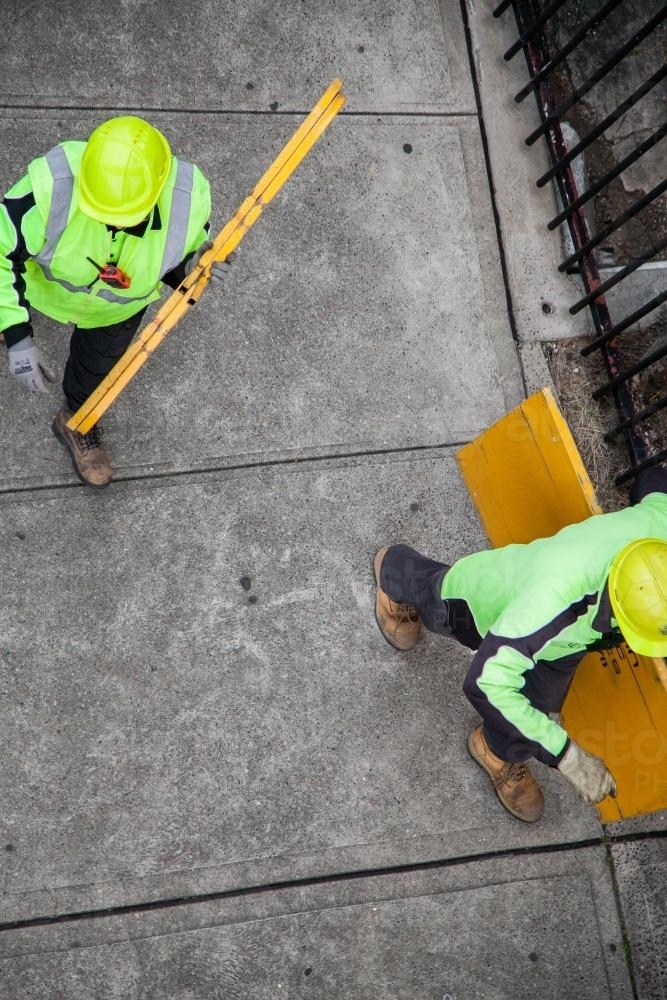 Overhead view of two workers in yellow carrying road signs - Australian Stock Image