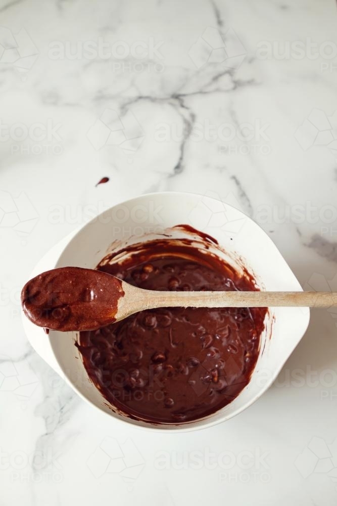 Overhead view of wooden spoon on a bowl of chocolate brownie mixture - Australian Stock Image