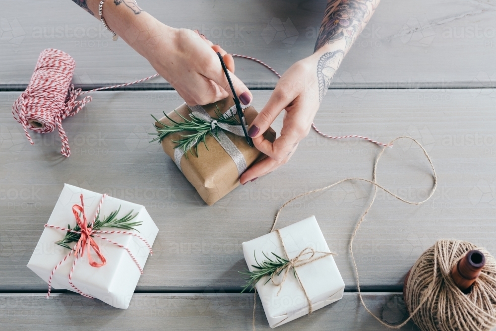 Overhead view of wrapping Christmas gifts and cutting ribbon - Australian Stock Image