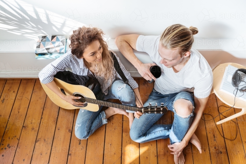 Overhead view of young couple relaxing with a guitar - Australian Stock Image