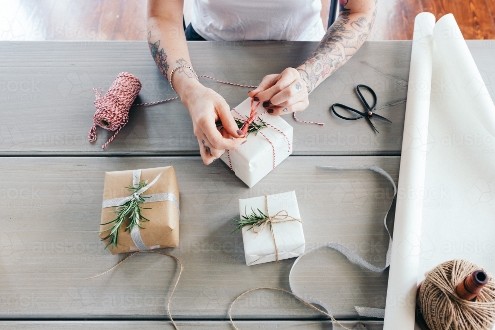 Overhead view of young girl wrapping Christmas presents in natural papers and twine - Australian Stock Image