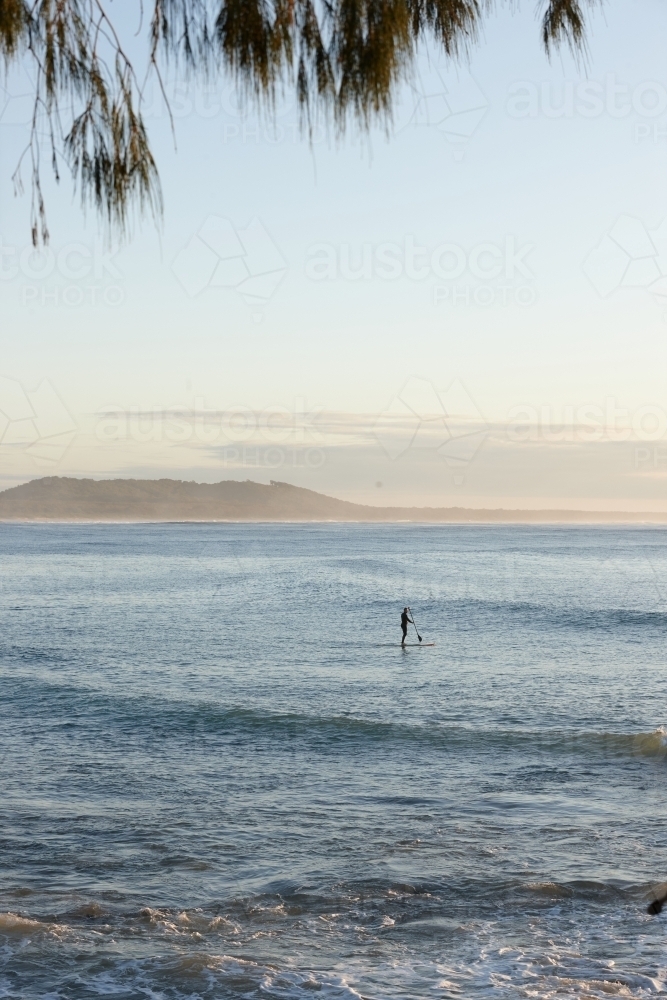 Paddle boarder on ocean at sunrise - Australian Stock Image