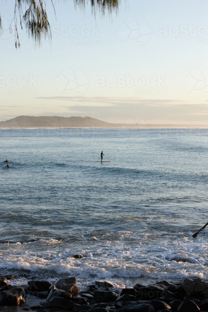 Paddle boarder on wave at sunrise - Australian Stock Image