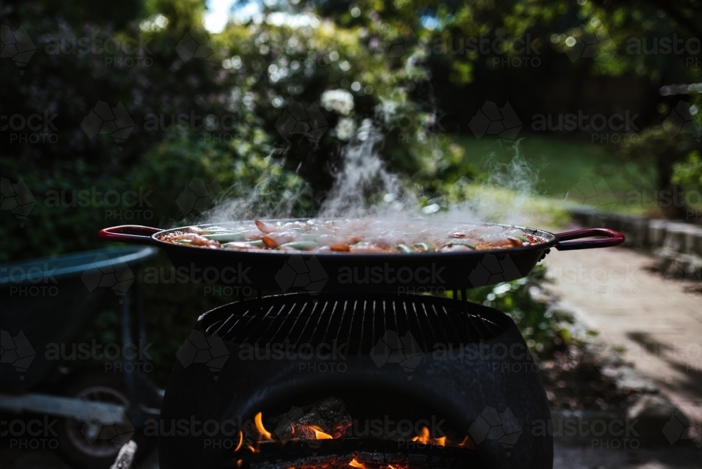 Paella cooks on an outdoor fire - Australian Stock Image