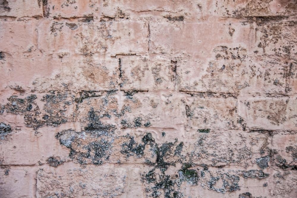 Paint peeling from faded pink brick wall - Australian Stock Image
