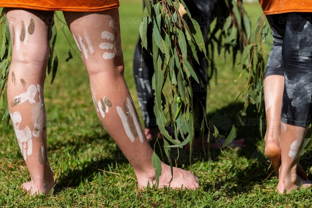 Painted legs of first nations dancers holding gum leaves for ceremony - Australian Stock Image