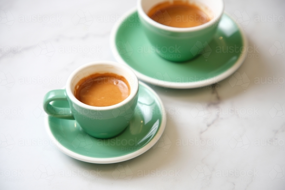 Pair of espressos in teal cup on marble table - Australian Stock Image
