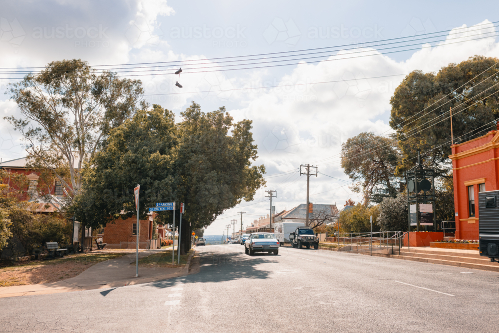 Pair of shoes hanging from power lines above urban street as vintage car passes underneath - Australian Stock Image