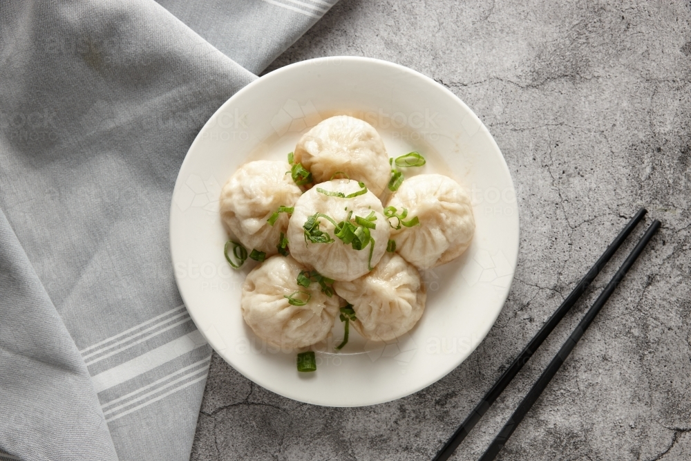 Pan fried pork buns served on a white plate garnished with green onions. : Austockphoto Pan fried pork buns served on a white plate garnished with green onions. - Australian Stock Image
