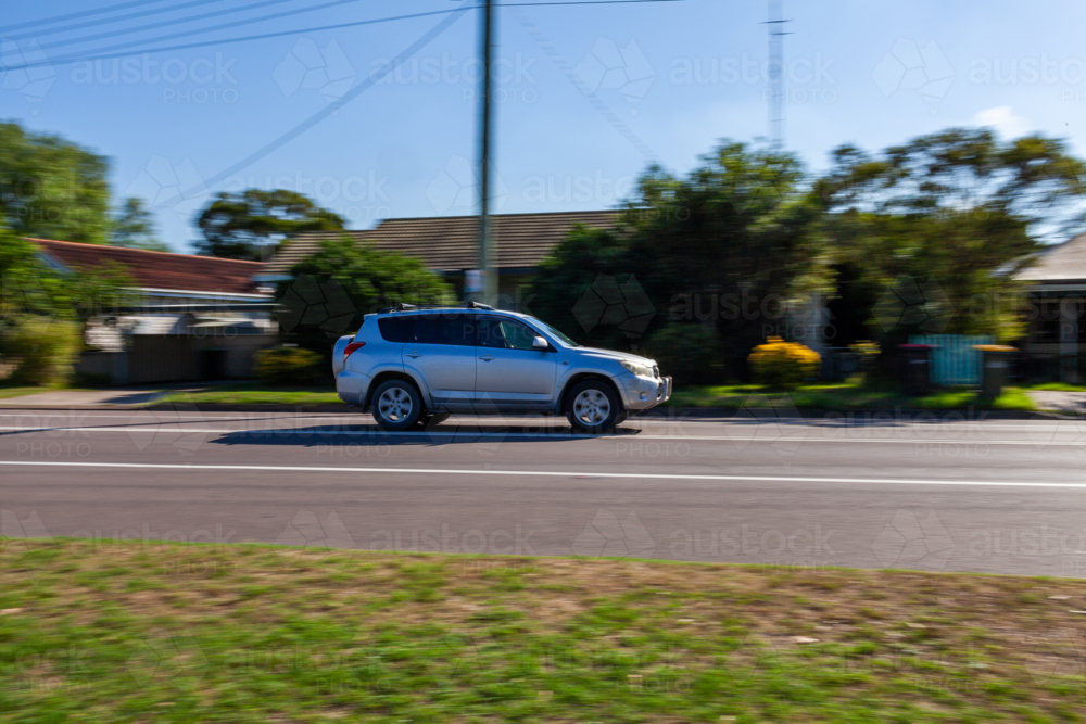 Panning shot of car vehicle traveling along highway through town - Australian Stock Image