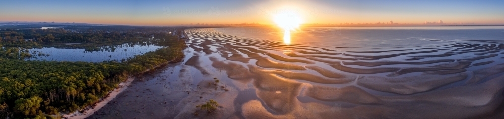 Panorama of coastline with ripples and patterns in the sand at sunrise - Australian Stock Image