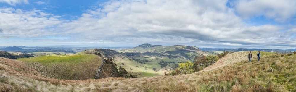 Panorama of hills and two people hiking together - Australian Stock Image