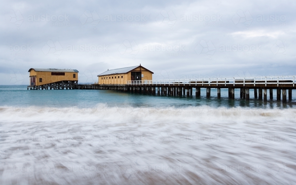 Panorama of long pier with boat sheds at end - Australian Stock Image