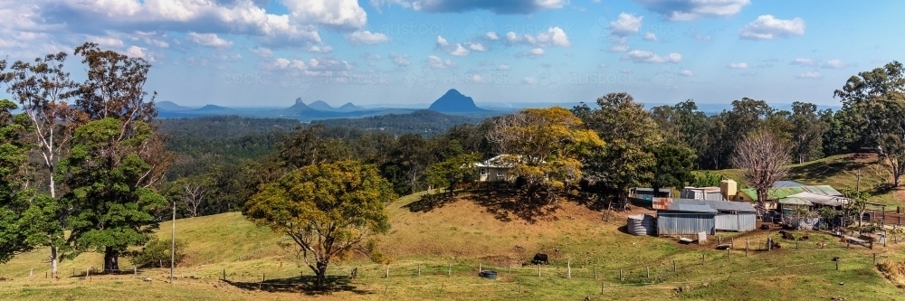 Panorama of property on farmland with bushland and mountains in background - Australian Stock Image
