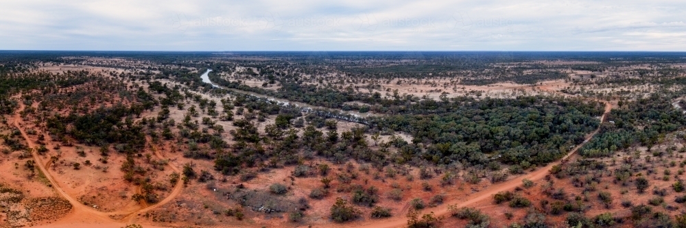 Panorama of red outback land with low green scrub - Australian Stock Image