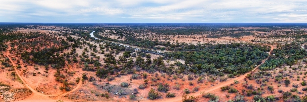 Panorama of red sand plains and mulga scrubs beside long, dusty tracks - Australian Stock Image