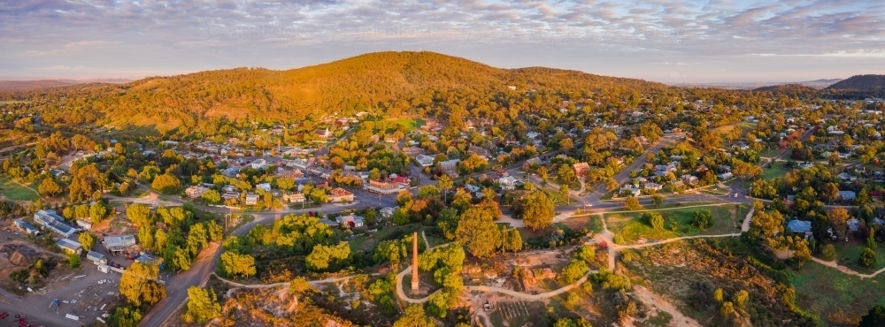 Panoramic aerial view of a rural town and mountain backdrop in early morning lighting - Australian Stock Image