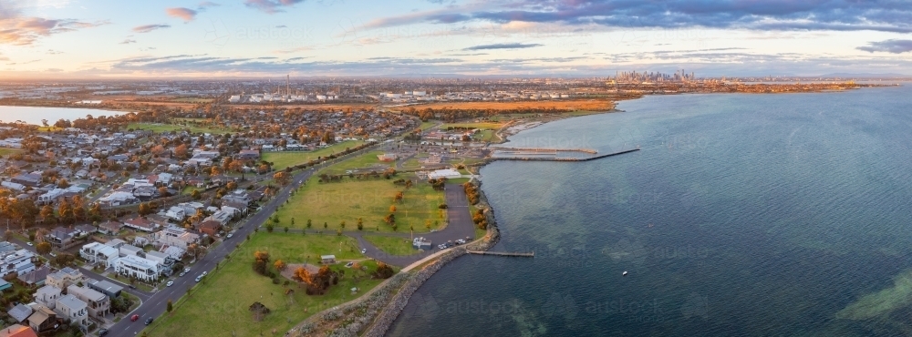 Panoramic aerial view of coastal reserve and parkland next to a calm bay at sunset - Australian Stock Image