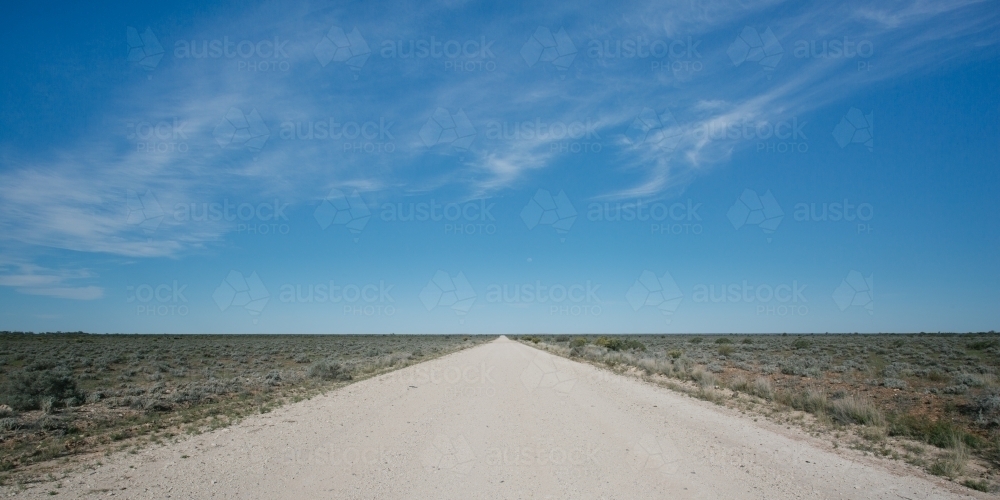 Panoramic view of a straight dirt road in the outback leading into the distance - Australian Stock Image