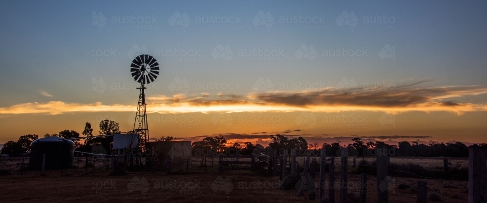 Panoramic view of countryside with a windmill silhouette - Australian Stock Image