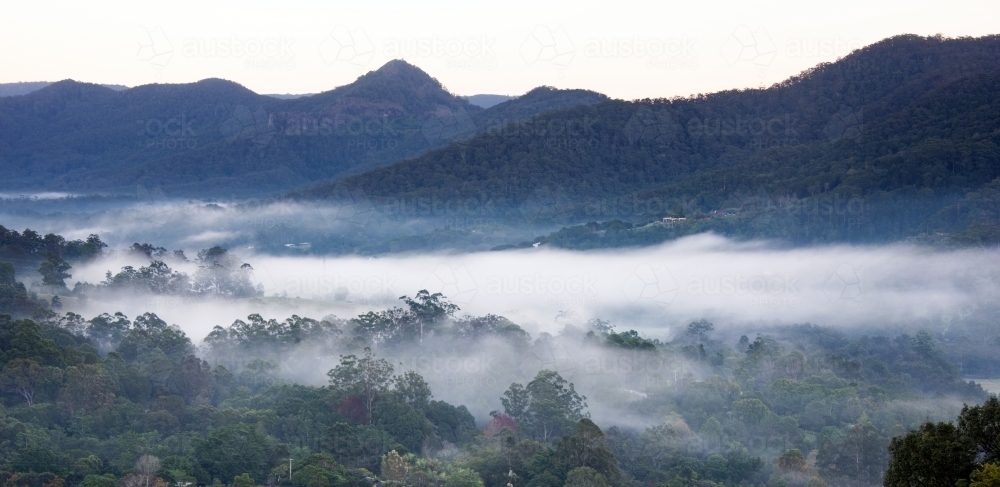 Panoramic view of misty valleys with mountains in the background. - Australian Stock Image