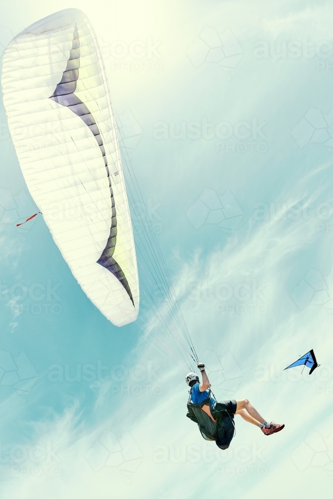 Para sailing with hang glider in the background on a sunny day - Australian Stock Image