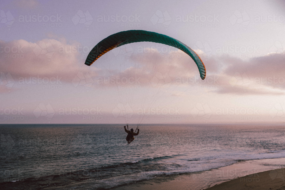 Paraglider soaring gracefully above the ocean at twilight - Australian Stock Image