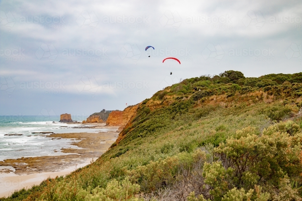 paragliders along coastline with lighthouse in background - Australian Stock Image