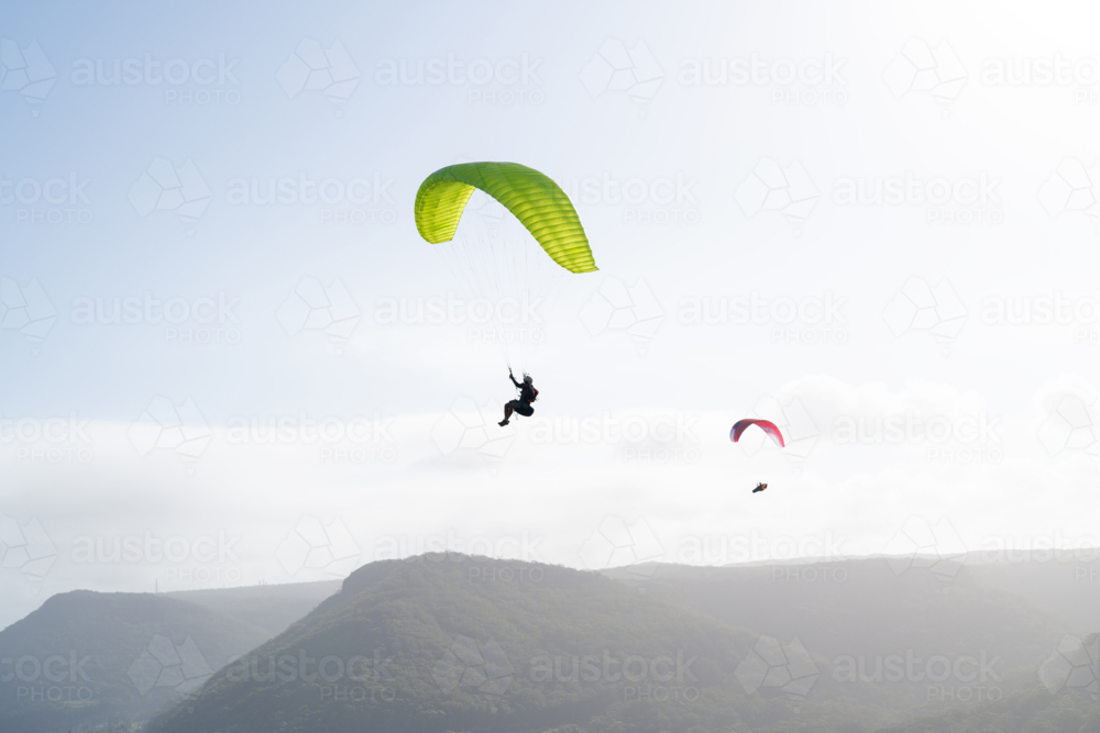 Paragliding against a brilliant sky and coastal mountain range - Australian Stock Image